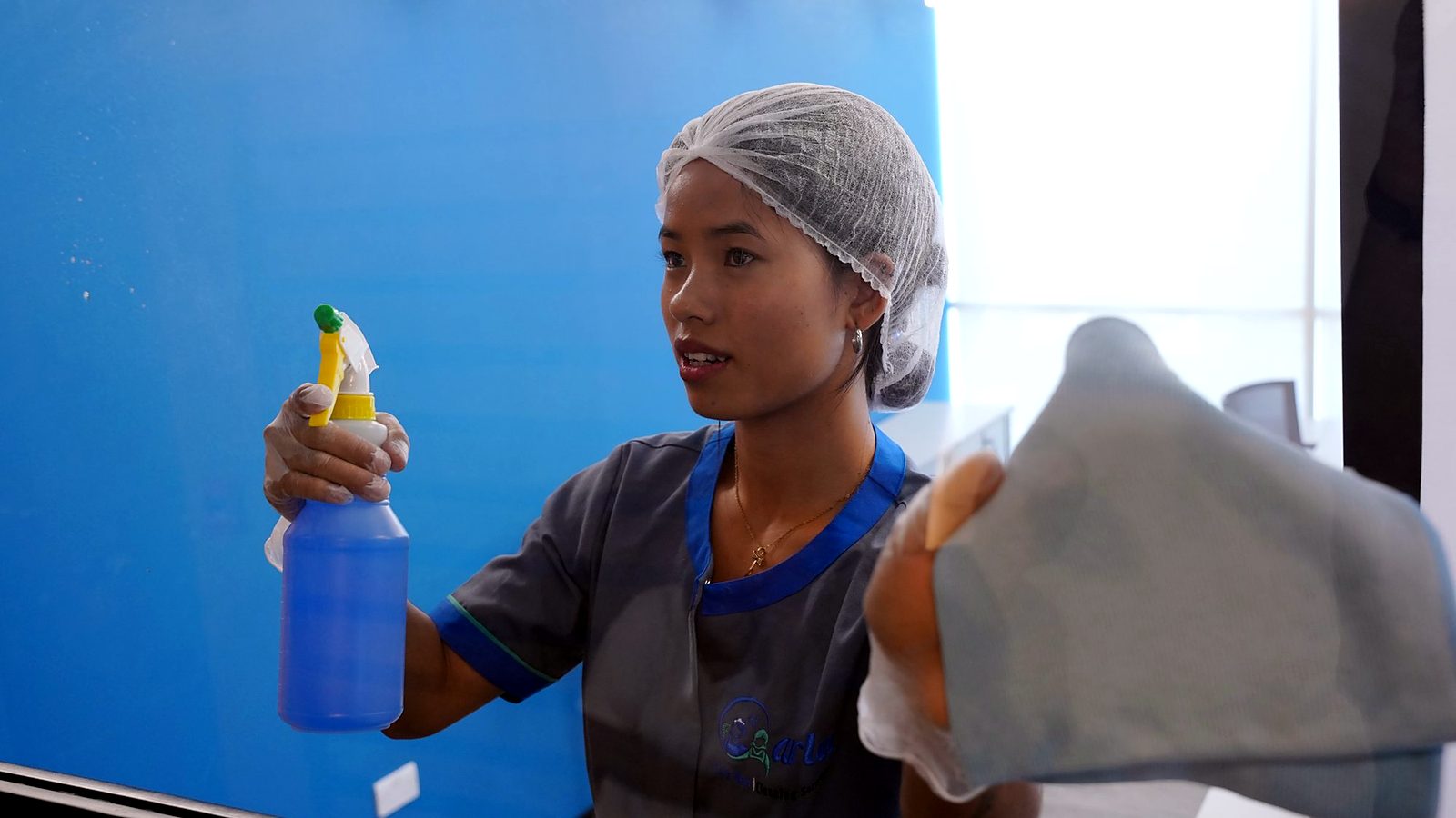 Carla Maid cleaner cleaning a glass wall in a building lobby in Doha