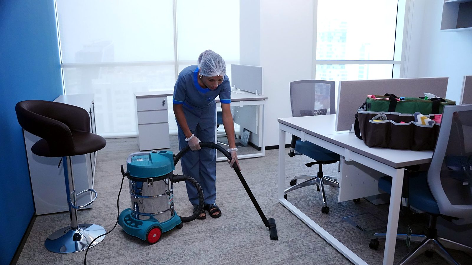 Carla Maid cleaner vacuuming a corridor floor in a building in Qatar