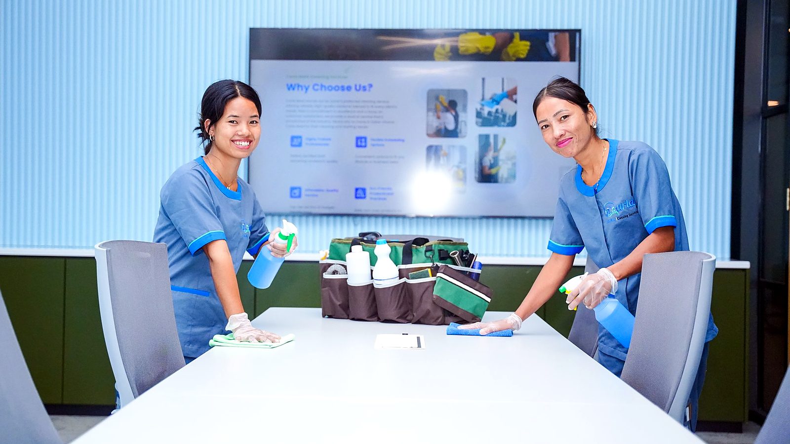Carla Maid team wiping a large meeting table in a Doha office