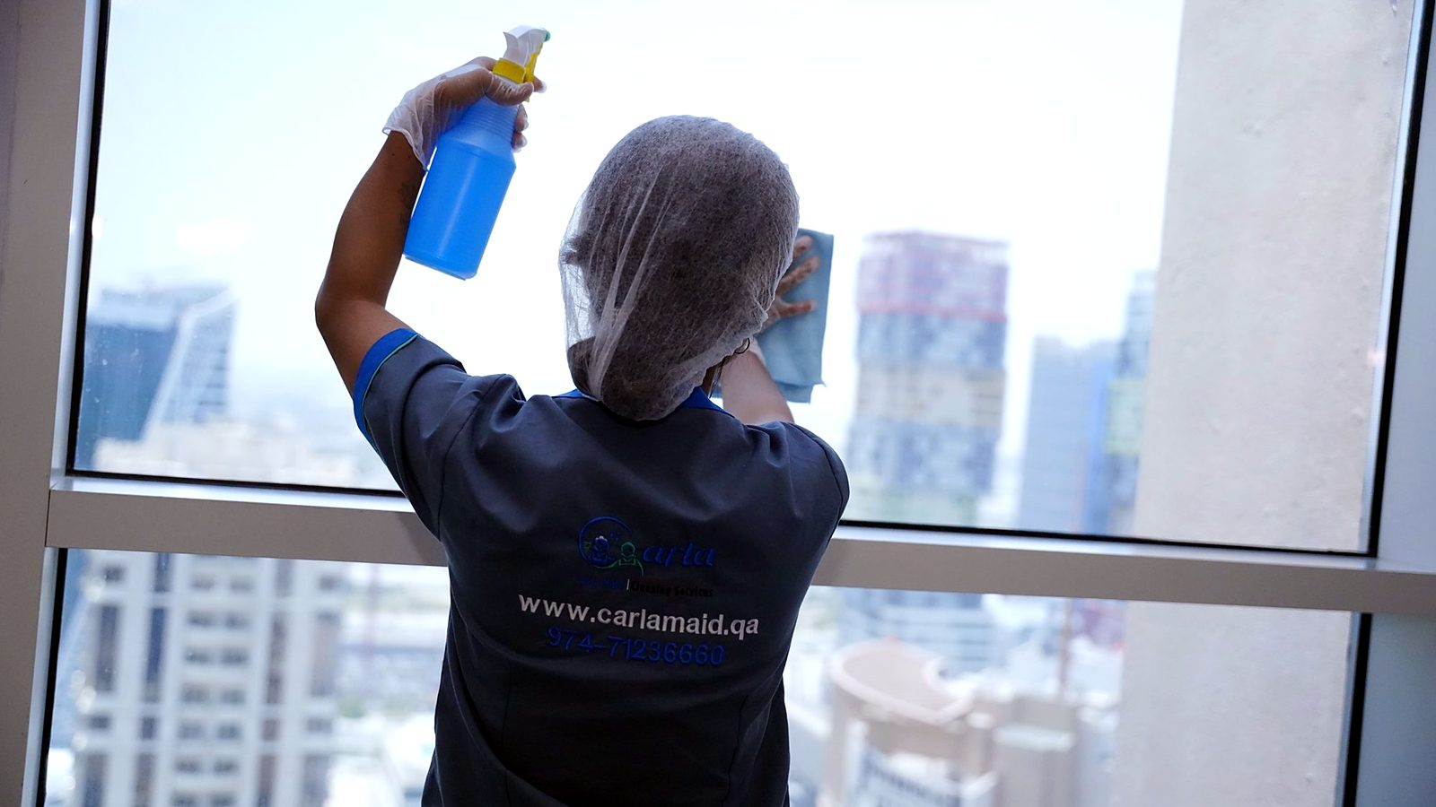 Building cleaning contract in Doha – Carla Maid cleaner cleaning windows in a high-rise building
